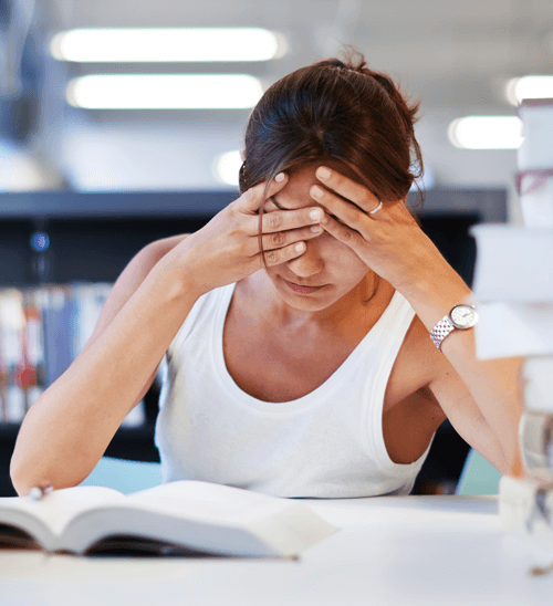 Stressed student studying for exams with a pile of books
