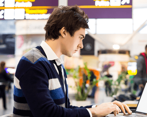 Young man working on a computer in a train station
